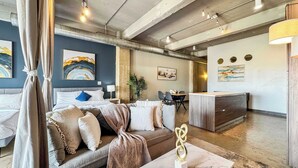A modern hotel room with a large bed, a sofa, a marble coffee table, and a dining area with a table and chairs. - Luxury 2BD | DT Dallas | Sleeps 14 | ValetParking (Dallas)