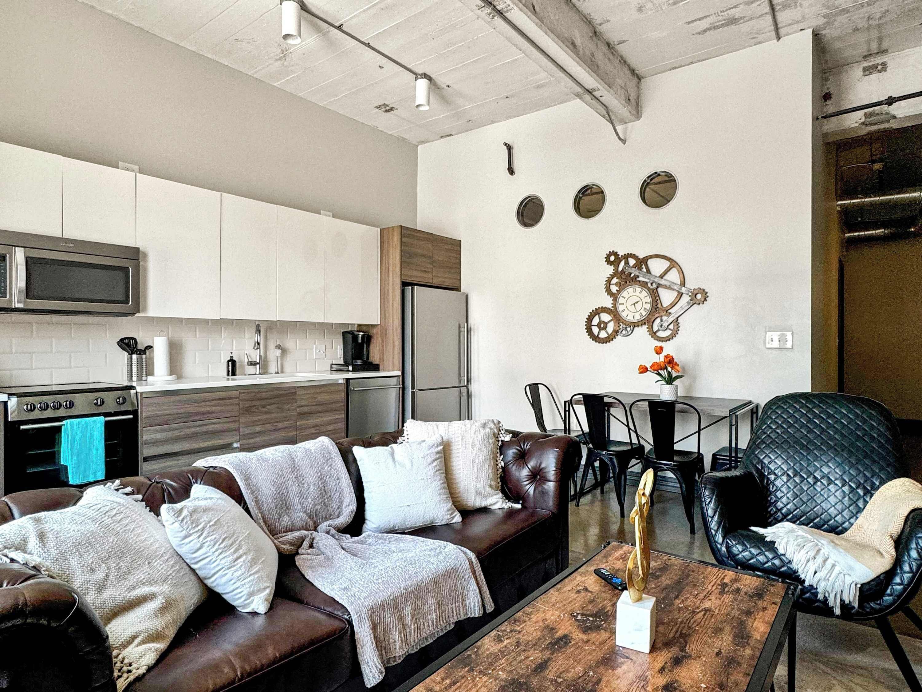 A modern kitchen with white cabinets, a microwave, and a stainless steel refrigerator.