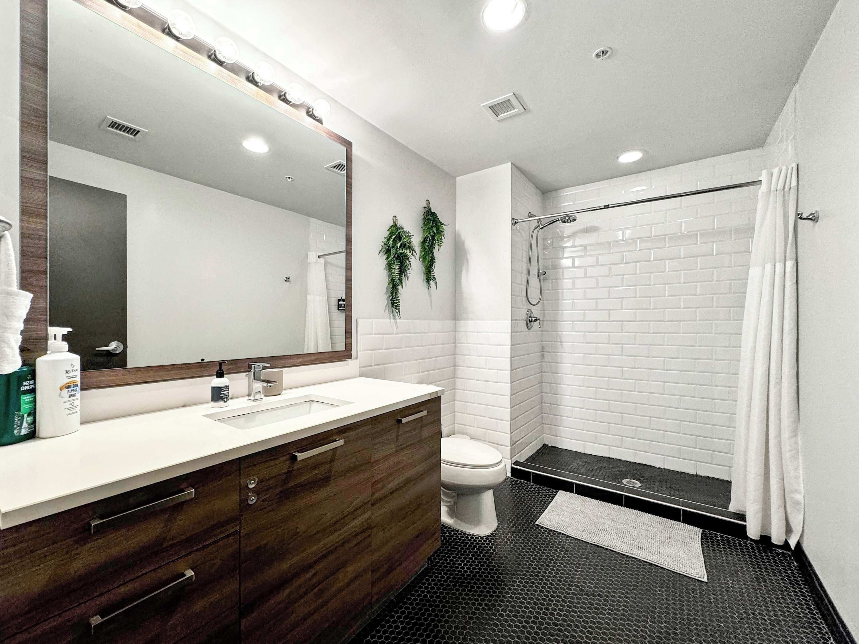 A modern bathroom with a vanity, mirror, and shower.