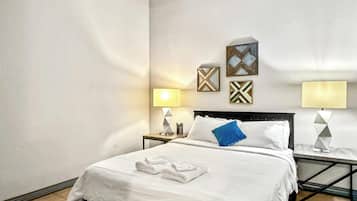 A hotel room with a bed, two bedside tables with lamps, and wall art.