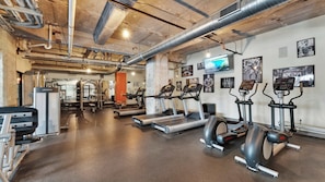 Ein Fitnessstudio mit Laufbändern, Crosstrainern und Gewichten.