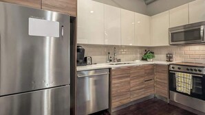 A modern kitchen with stainless steel appliances, wooden cabinets, and a tiled backsplash. - Elegant 3BD | DT Dallas | Sleeps 9 | ValetParking (Dallas)