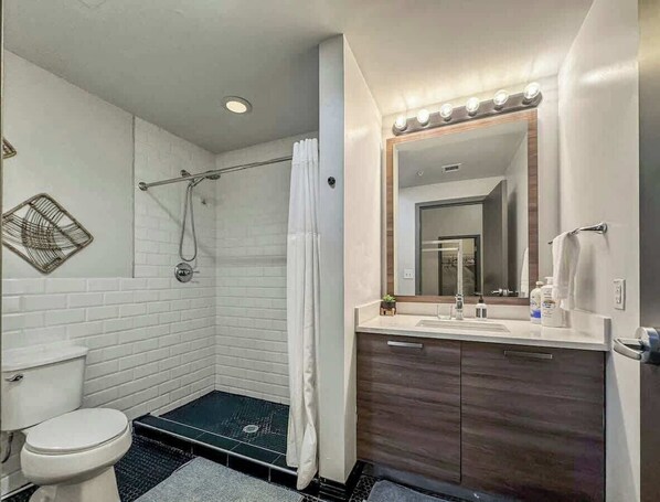 A modern bathroom with a shower, toilet, and vanity.