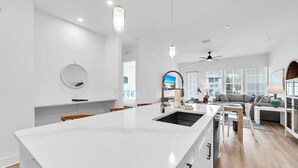 Cocina moderna con una isla grande, armarios blancos y vista al área de estar.