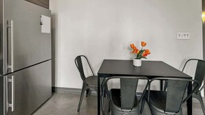 A compact kitchen with a built-in refrigerator, a dining table with chairs, and a small potted plant on the table.