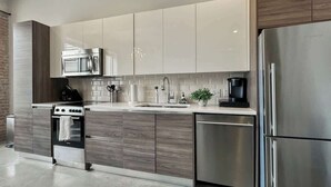 A modern kitchen with stainless steel appliances, wooden cabinets, and a built-in dishwasher.