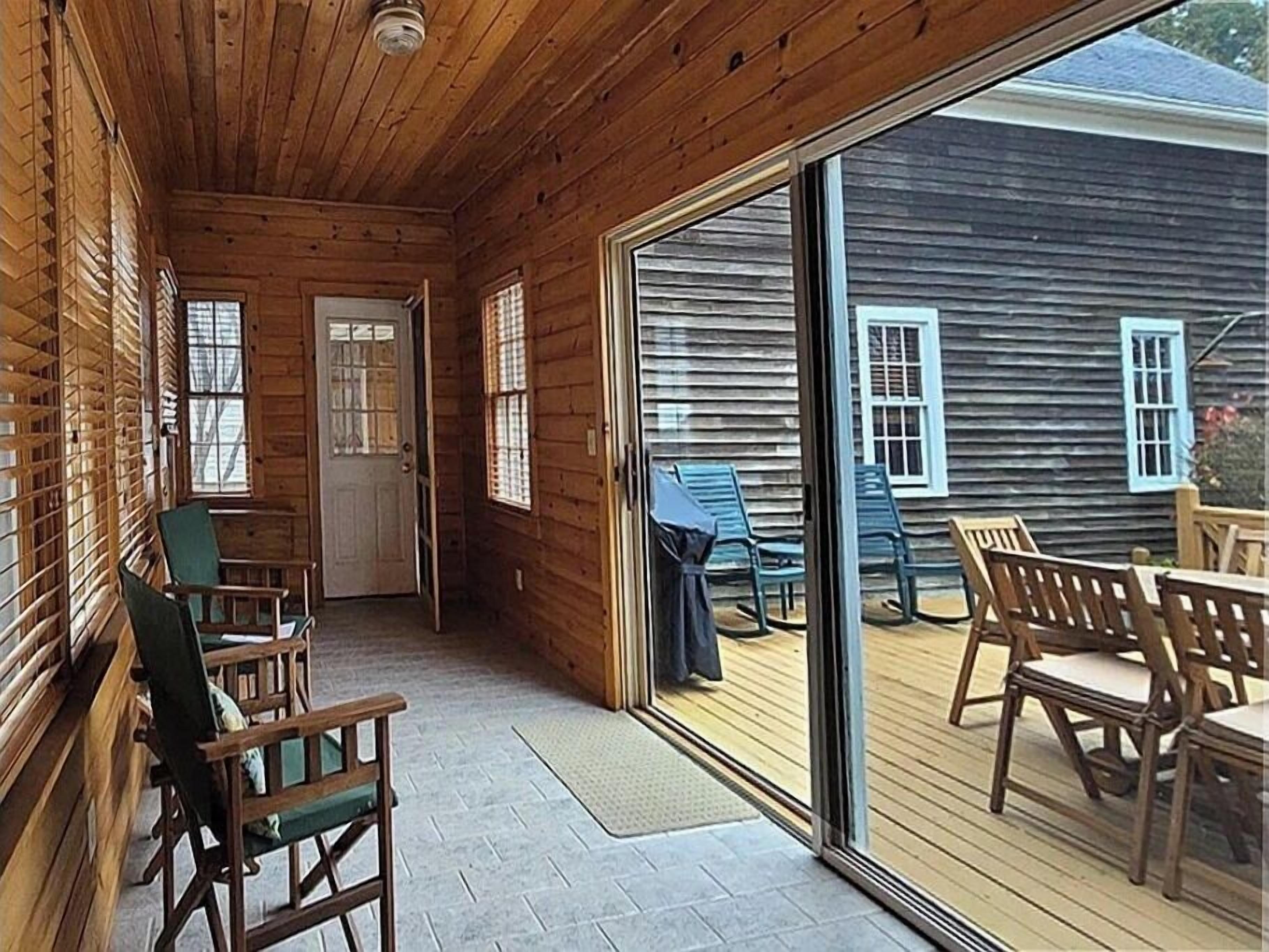 A wooden cabin with a covered porch, sliding glass doors, and outdoor seating.