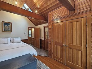 Een slaapkamer met een groot bed, een houten garderobe en een dakraam.