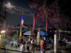 A courtyard with flags, a view of a cityscape, and potted plants. - Zimba Happy Home Stay (Darjeeling)