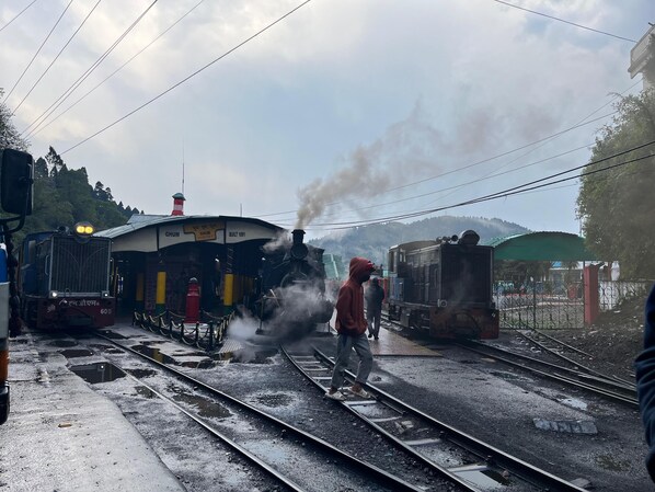 A steam locomotive at a railway station with tracks and a platform. - Zimba Happy Home Stay (Darjeeling)
