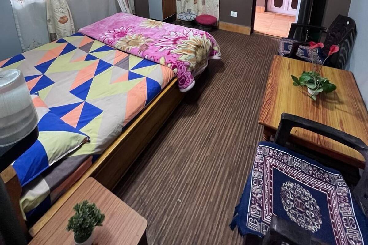 A hotel room with a bed, a desk with a chair, a TV, and a door leading to another room.
