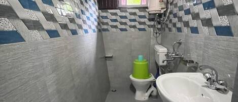 Un baño pequeño con inodoro, bidé y lavamanos. Las paredes están cubiertas con un diseño de mosaico a cuadros.