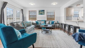 Uma sala de estar moderna com sofá, mesa de centro e um espaço bar com banquetas.