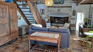 A rustic interior with a wooden staircase, a fireplace, and a cozy seating area. - Stone House by Beach in Pont-aven (Tregunc)