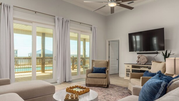 A spacious living room with a large TV, comfortable seating, and a view of a pool. - NEW! "Days Like This" 5/5, Private POOL, Sleeps 14, Easy Gulf Beach Access (Dauphin Island)
