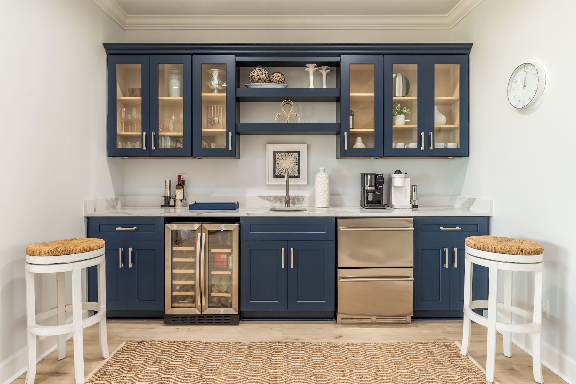 A modern kitchen with dark blue cabinets, stainless steel appliances, and a patterned rug.