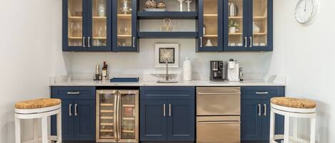 A modern kitchen with dark blue cabinets, stainless steel appliances, and a patterned rug.