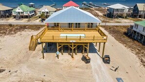 A beachfront property with a large wooden deck, a covered swimming area, and a view of the ocean. - NEW! "Days Like This" 5/5, Private POOL, Sleeps 14, Easy Gulf Beach Access (Dauphin Island)