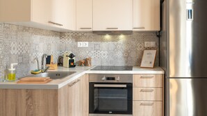 A modern kitchen with light wood cabinets, a stainless steel refrigerator, a built-in oven, and a patterned backsplash. - 2BD Modern Home Steps from Pasalimani (Pireas)