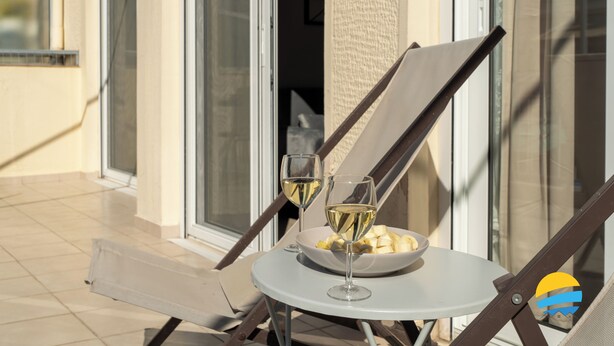 A table with two glasses of white wine and a bowl of fruit on a sunny terrace. - 2BD Modern Home Steps from Pasalimani (Pireas)