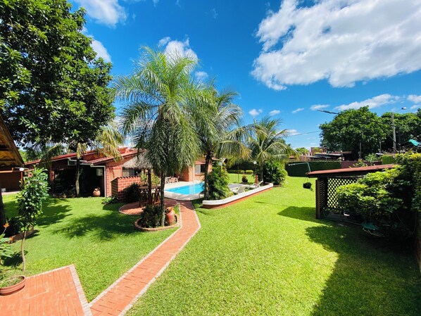 Um quintal bem cuidado com piscina, um pátio de tijolos e vegetação exuberante.