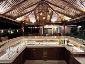 An outdoor bar area with a thatched roof, wooden beams, and hanging lanterns. - Casa Por Temporadas (Santa Cruz)
