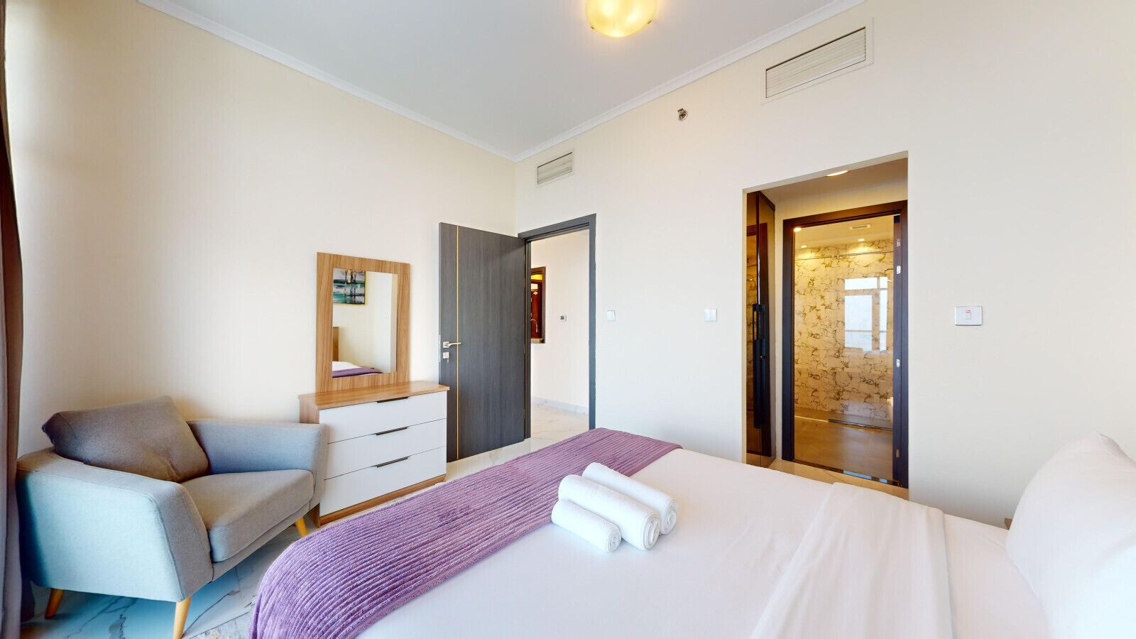 Et moderne hotelværelse med seng, skrivebord, stol og garderobeskab.