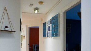 En smal hall med ett mönstrat mattgolv som leder till ett sovrum med en säng och ett nattduksbord.