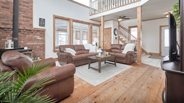 A spacious living room with leather sofas, a wooden coffee table, and a staircase leading to a loft.