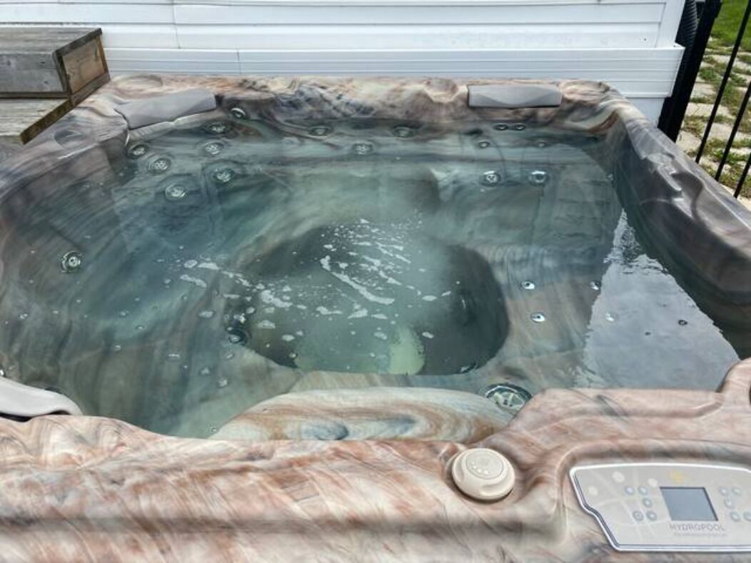 A hot tub with a control panel, surrounded by a wooden deck.