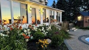 A modern house with a covered porch, a hot tub, and a landscaped garden with various plants and flowers.