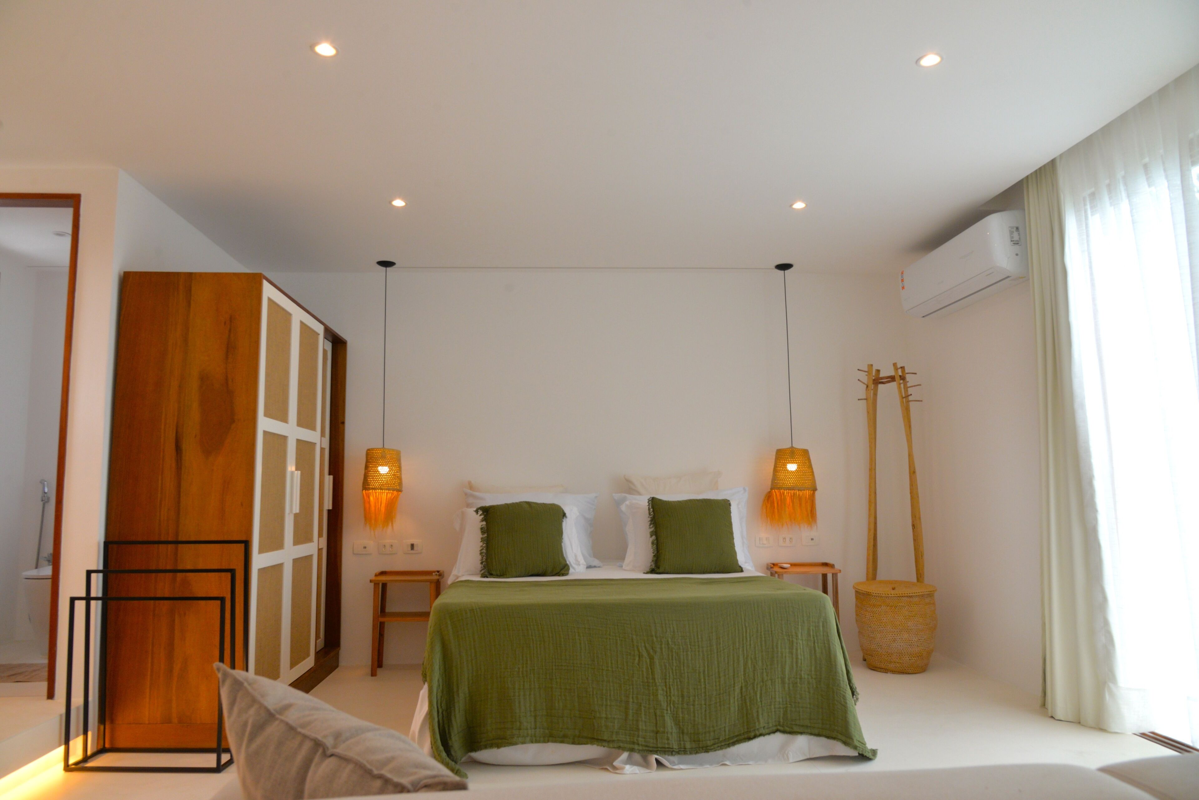 Un dormitorio con cama, mesitas de noche, una lámpara de pie y una ventana con cortinas.