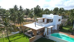 A modern house with a pool, surrounded by palm trees and a well-maintained lawn. - Kite Villas - Ilha do Farol (Itarema)