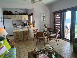 Uma cozinha compacta com área de refeições, um ventilador de teto e vista para uma área externa através de uma porta de correr de vidro.