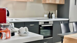 A modern kitchen with a white countertop, a red appliance, and a glass jar of snacks. - Alight Sauna and SPA Penthouse (Xewkija)