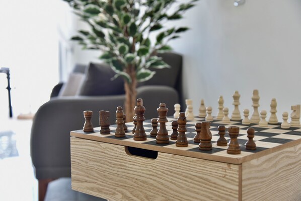 A chessboard on a wooden table with a plant in the background. - Alight Sauna and SPA Penthouse (Xewkija)