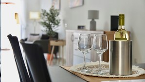 A dining table with a bottle of wine, two glasses, and a placemat. - Alight Sauna and SPA Penthouse (Xewkija)