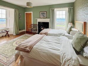 A room with two beds, a fireplace, a window with a view, and a door.