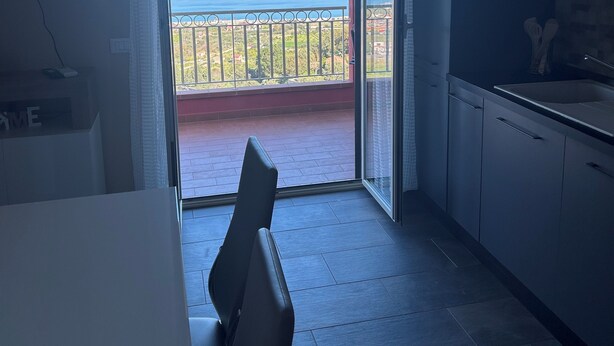 A modern kitchen with a large sliding glass door leading to a balcony with a view of the sea. - Panorama d'oro (Sicilia)