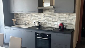 A modern kitchen with grey cabinets, a built-in oven, and a stone backsplash. - Panorama d'oro (Sicilia)