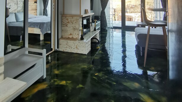 A room with a wet floor, a bed, a TV, and a window with curtains.