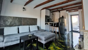 A modern living room with a sofa, a coffee table, and a kitchen in the background.