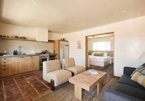 Un espacio habitable compacto con cocina, dos sillones, una mesa de centro y un sofá.