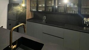 A modern kitchen with dark cabinetry, a black countertop, and pendant lighting. - Far from nothing and close to everything.  (AN)