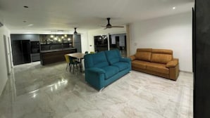 A modern living room with a blue sofa, a brown sofa, and a dining area with a table and chairs. - Far from nothing and close to everything.  (AN)