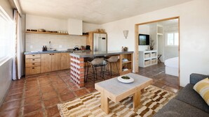 Een moderne keuken met een centraal kookeiland, barkrukken en een eethoek met tafel en stoelen.