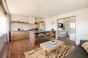Uma cozinha moderna com uma ilha central, banquetas de bar e uma área de refeições com mesa e cadeiras.