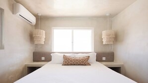 Een slaapkamer met een groot bed, twee bedlampjes en een raam.