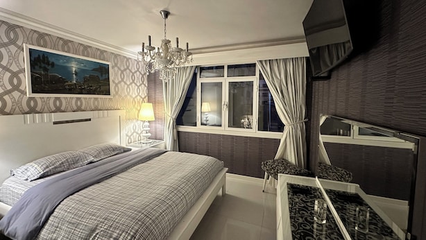 A bedroom with a bed, bedside table, lamp, window with curtains, and a chandelier. - Departamento Por Temporadas (La Paz)