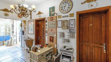 A room with a large clock, a reception desk, and various framed items on the wall.